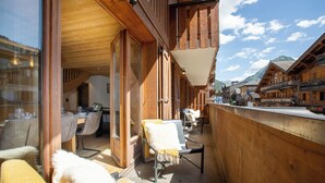 Een houten balkon met stoelen en een tafel, met uitzicht op een bergachtig gebied.