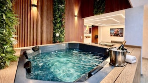 Ein Whirlpool mit einer Champagnerflasche, umgeben von Holzverkleidung und Grünpflanzen.