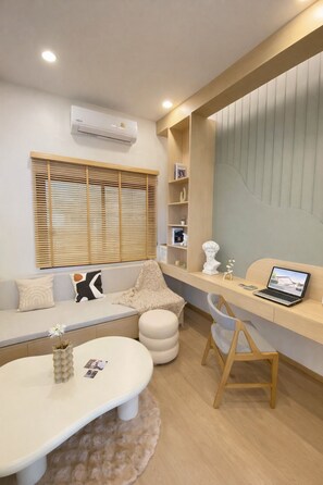 A modern room with a sofa, a desk with a laptop, a small round table, and a decorative vase. - Coxy 2-bedroom house with AC in charming Near Bangtao Beach Phuket (Thalang District)