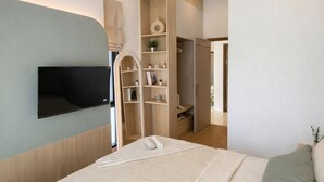 Una camera da letto moderna con un letto, una TV a parete, scaffalature integrate e un armadio.