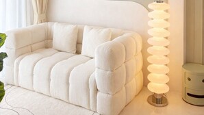 Camera da letto moderna con un divano trapuntato, una testiera particolare e una lampada da terra.