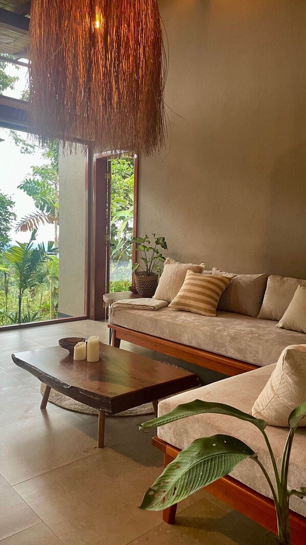 A modern living room with a sofa, a coffee table, and a hanging light fixture.