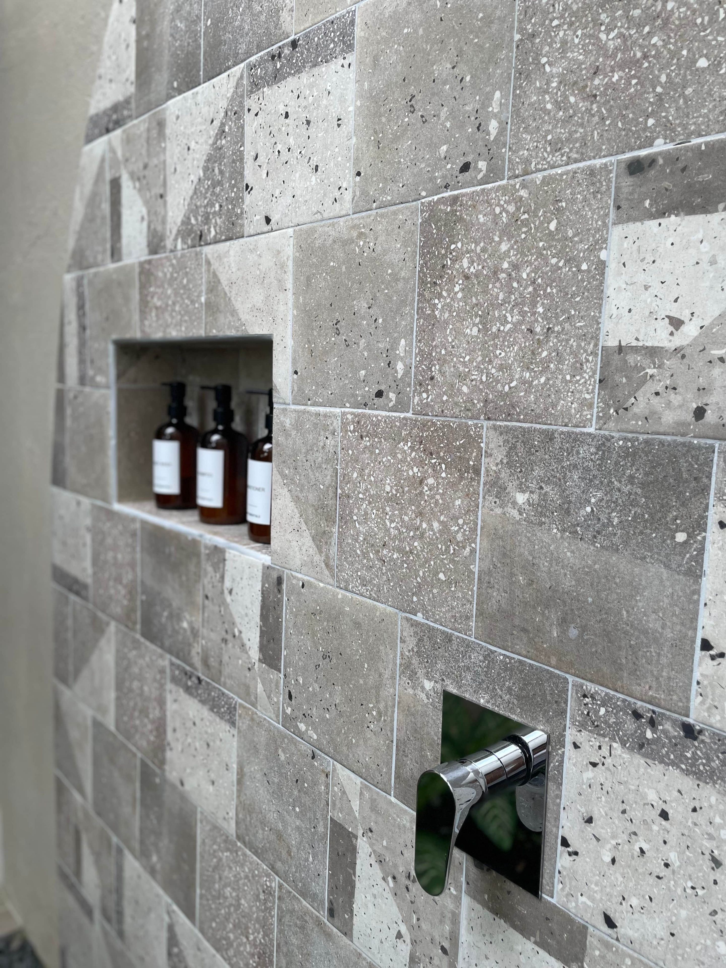 Pared de baño con salpicadero de azulejos y estante para dispensador de jabón empotrado.