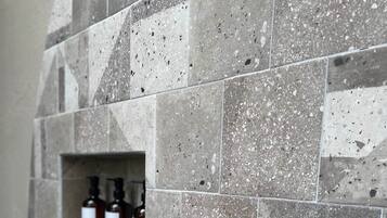 Pared de baño con salpicadero de azulejos y estante para dispensador de jabón empotrado.