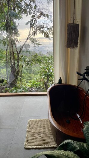 A room with a view of a forest, a wooden bathtub, and a woven mat on the floor. - Jungle Villa (Puyo)