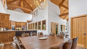 Une cuisine spacieuse avec des meubles en bois, une grande table à manger et un lustre.
