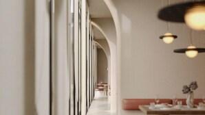 A restaurant with a long, arched corridor leading to seating areas. Tables are arranged along the corridor with overhead lighting. - Latyrian Hotel (Durrës)