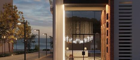 A modern hotel entrance with a glass facade, a reception desk, and a landscaped area with trees.