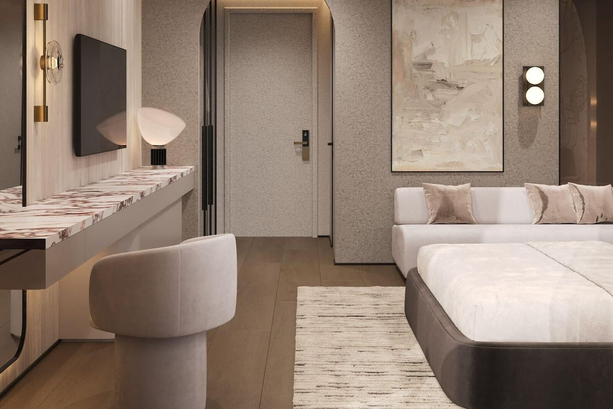 A modern bedroom with a bed, bedside table, lamp, and artwork.