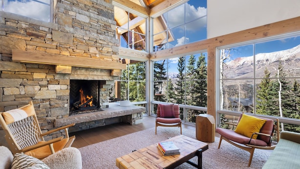 A stone fireplace, cozy seating, and a large window with a mountain view. - Ski In/Out, Hot tub, Sauna, Fireplaces, Fire Pit, Game Room (Mountain Village)