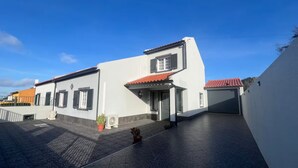 Een woongebouw met een betegeld terras, een kleine tuin en een rode dakbedekking.