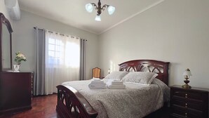 Een slaapkamer met een houten bed, een kaptafel, een spiegel en een kroonluchter.