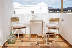 Ein Balkon mit zwei Stühlen, einem kleinen Tisch und einer grünen Flasche.