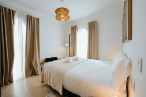 Hotellihuone, jossa on sänky, yöpöytä, lamppu ja verhot.