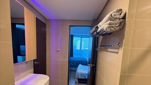 Un bagno moderno con un mobile lavabo, un portasciuga e vista su una camera da letto.