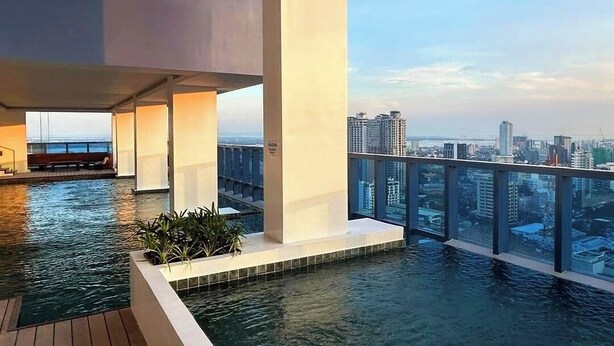 Una piscina a sfioro sul tetto con vista sulla città, caratterizzata da ampie colonne e ringhiera in vetro.