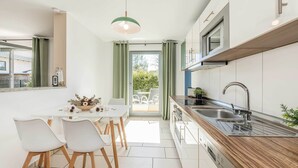 A modern kitchen with a wooden countertop, stainless steel sink, and a dining area with a white table and chairs. - Vacation apartment in Zinnowitz with terrace, WLAN & playground - ideal for families (Zinnowitz)