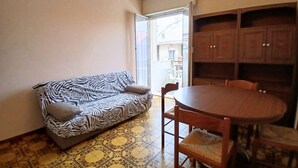 A living room with a zebra-patterned sofa, a round wooden dining table with chairs, and a patterned floor. - RG006 - Bellaria, comfortable two-room apartment with sea view (Bellaria-Igea Marina)
