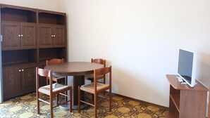 A room with a round wooden table, two chairs, a TV on a stand, and built-in wooden cabinets. - RG006 - Bellaria, comfortable two-room apartment with sea view (Bellaria-Igea Marina)