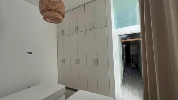 Habitació amb un armari ampli, una làmpada penjant i vista a un altre espai.