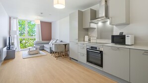 Una cocina moderna con electrodomésticos integrados, un comedor con sofá y sillones, y vistas a zonas verdes.
