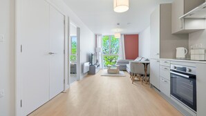 Una cocina moderna con electrodomésticos integrados, un comedor con mesa y sillas, y un sofá.