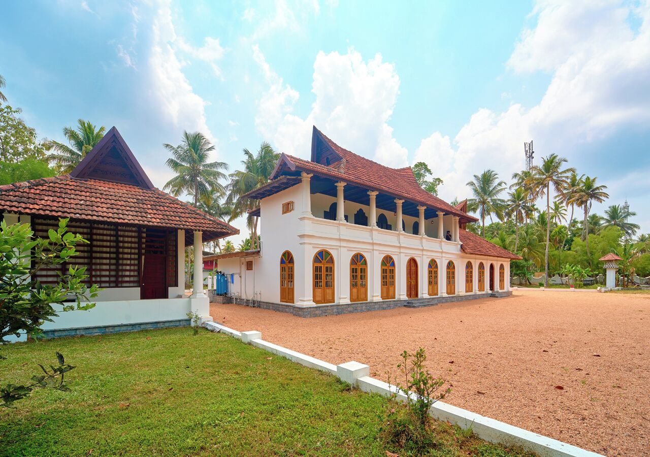 A large building with a tiled roof, multiple arched doorways, and a courtyard.