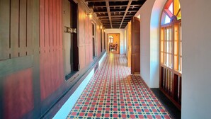 A hallway with patterned flooring, wooden walls, and arched windows.