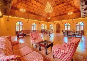 A spacious room with wooden flooring, large arched windows, and a chandelier. - Kuttanad Manor by VOYE HOMES Alleppey (Kuttanad Taluk)
