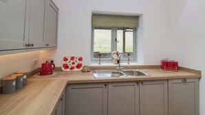 A kitchen with a window, a sink, and cabinets. - High Birks Barn (Sedbergh)