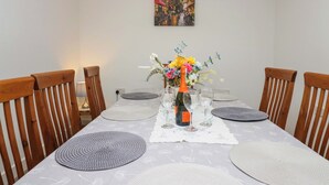 A dining table with placemats, a bottle of champagne, and a floral centerpiece. - High Birks Barn (Sedbergh)