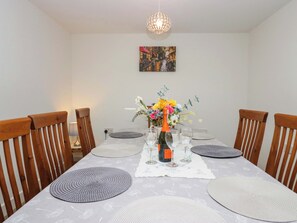 A dining table with placemats, a bottle of champagne, and a floral centerpiece. - High Birks Barn (Sedbergh)