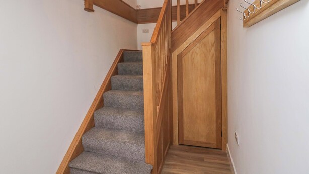 A wooden staircase with carpeted steps leading to a door. - High Birks Barn (Sedbergh)