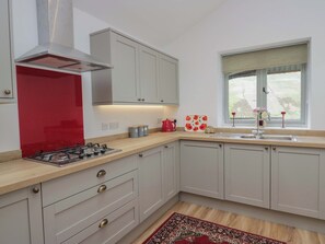 A kitchen with a gas stove, a red backsplash, and a window with a view. - High Birks Barn (Sedbergh)