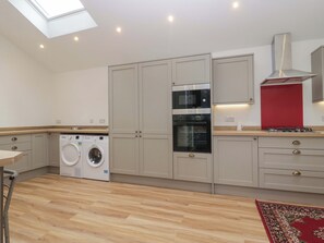 A modern kitchen with built-in appliances, a washing machine, and a skylight. - High Birks Barn (Sedbergh)