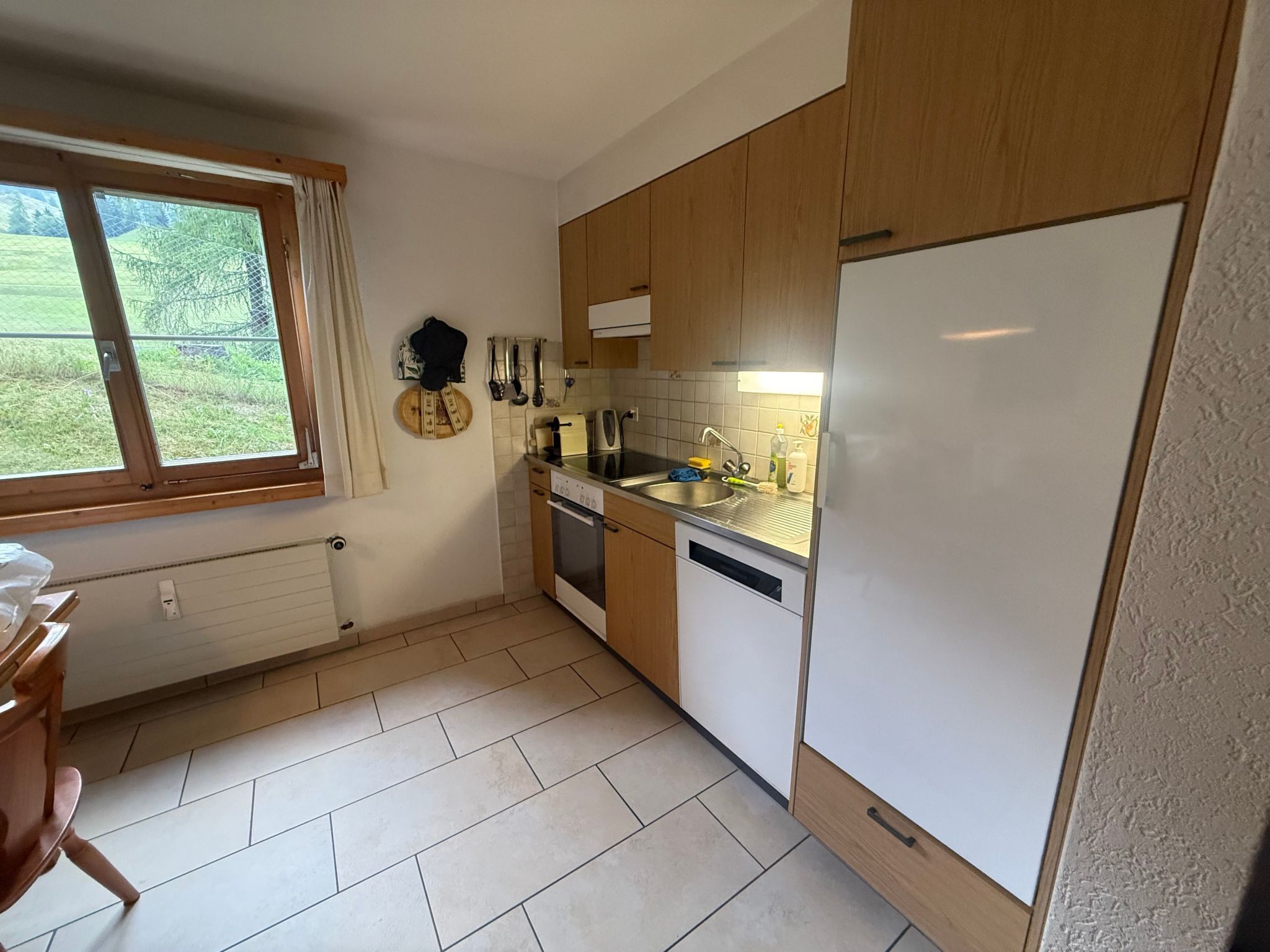 Eine kleine Küche mit Holzausstattung, einem integrierten Geschirrspüler und einem Kühlschrank.
