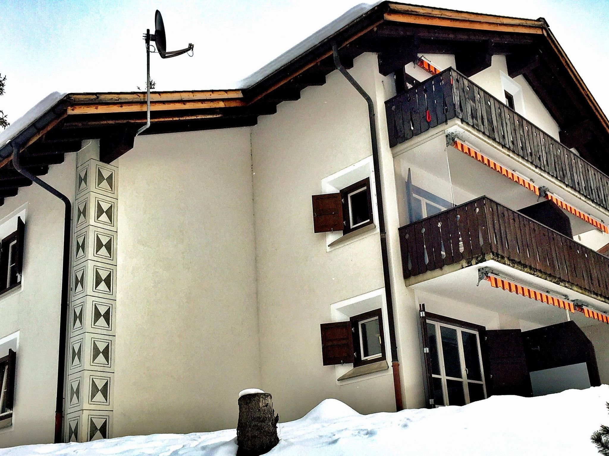 A multi-story building with a snow-covered roof and a satellite dish.