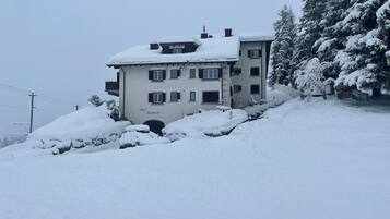 Un immeuble à plusieurs étages, dont le toit est recouvert de neige, et sur lequel on peut lire l’inscription « Chasa Rieseant ».