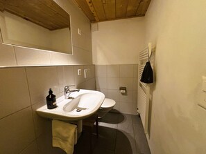 Ein Badezimmer mit Waschbecken, Toilette und einem Handtuch an der Wand.
