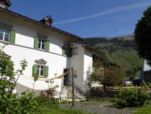 Un bâtiment à deux étages doté d’un balcon, d’un escalier et d’un espace jardin avec des sièges extérieurs.