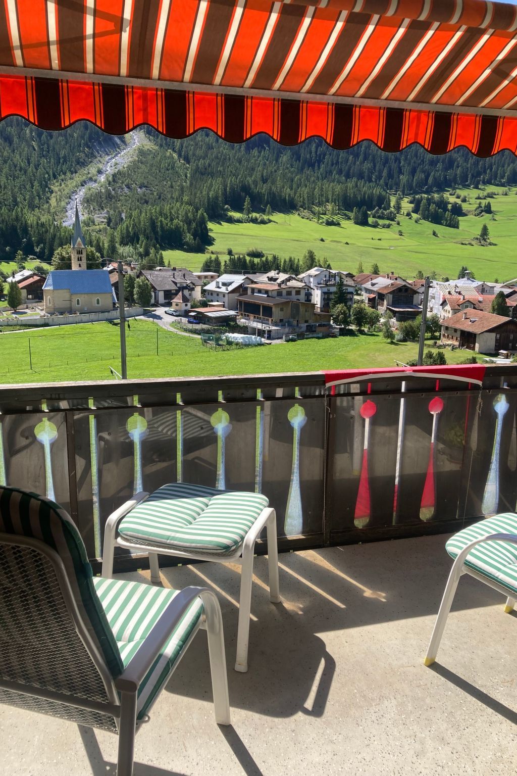 Ein Sitzbereich im Freien mit Stühlen und Blick auf ein Dorf.