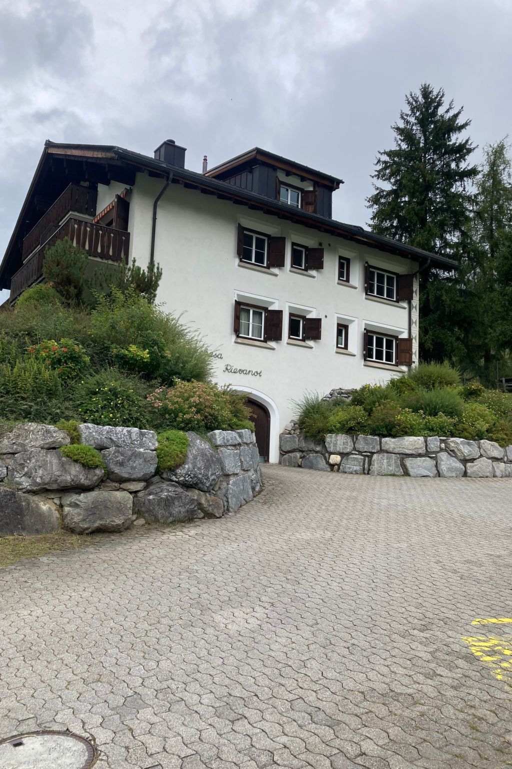 Un immeuble à plusieurs étages, doté d’une façade en pierre, d’un balcon en bois et d’une plaque portant son nom.