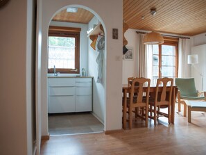 Eine Küche mit Fenster, Holzschränken und einem Essbereich mit Stühlen und Tisch.
