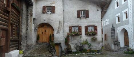 Un bâtiment traditionnel avec une porte en bois, un petit porche et un mur en pierre.