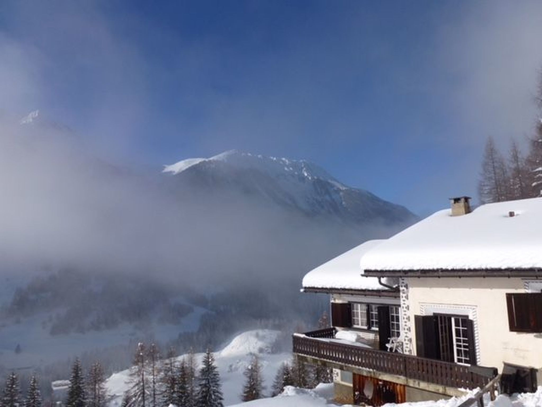 A snow-covered mountain with a building in the foreground.