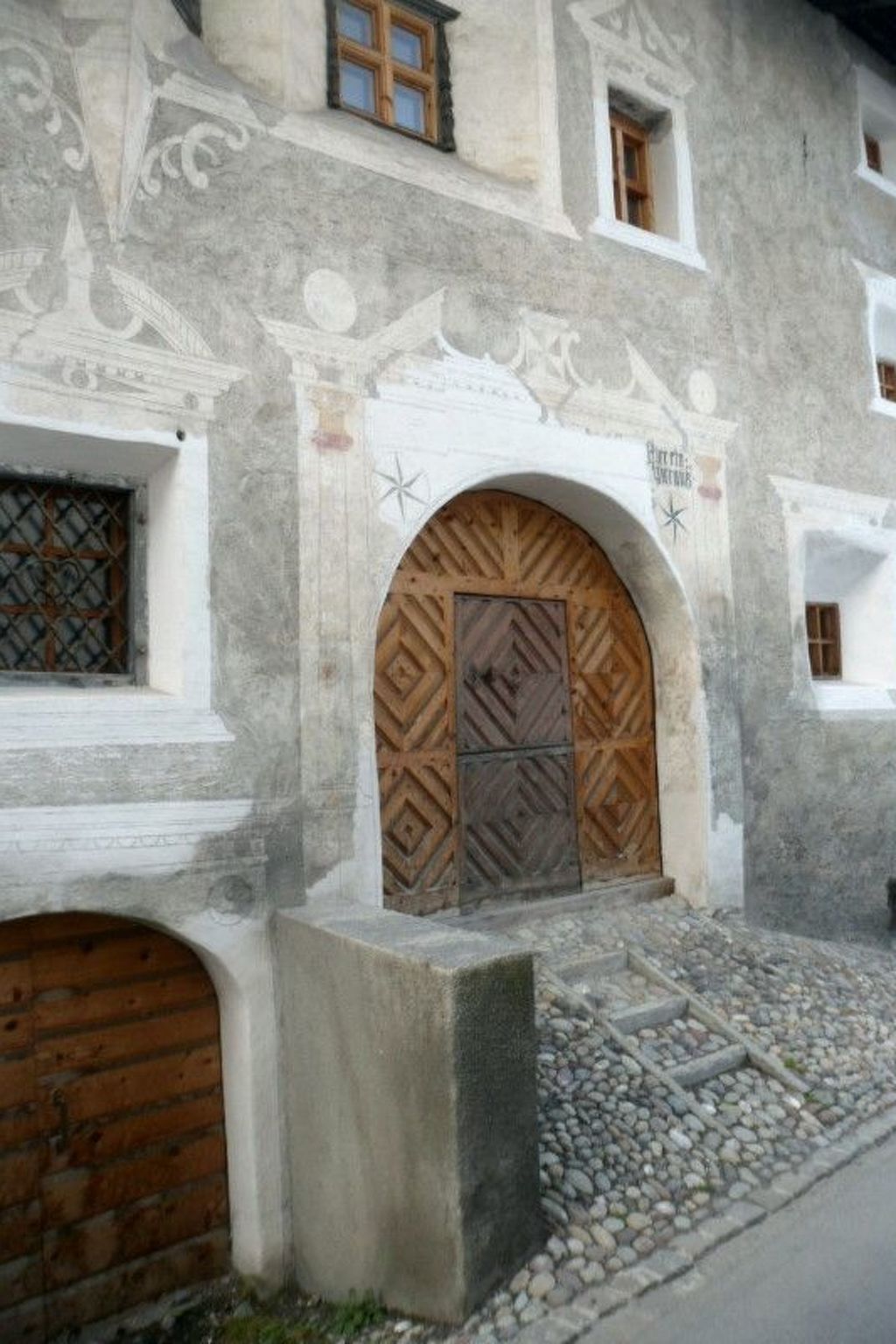 Un edificio con una entrada arqueada grande, una ventana pequeña y un camino de piedra que conduce a la entrada.