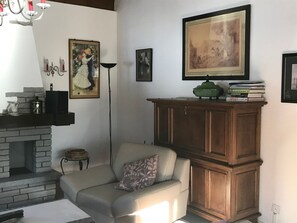 A living room with a fireplace, a sofa, a cabinet, and various framed artworks. - Chesa Giattin, (Bergün/Bravuogn), 150 by Interhome (Bergün)