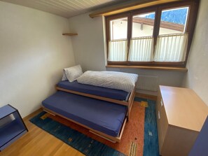 A room with a bed, a small table, and a window with a view. - Casa Crispalt Monn, (Sedrun), 187.03 by Interhome (Sedrun)