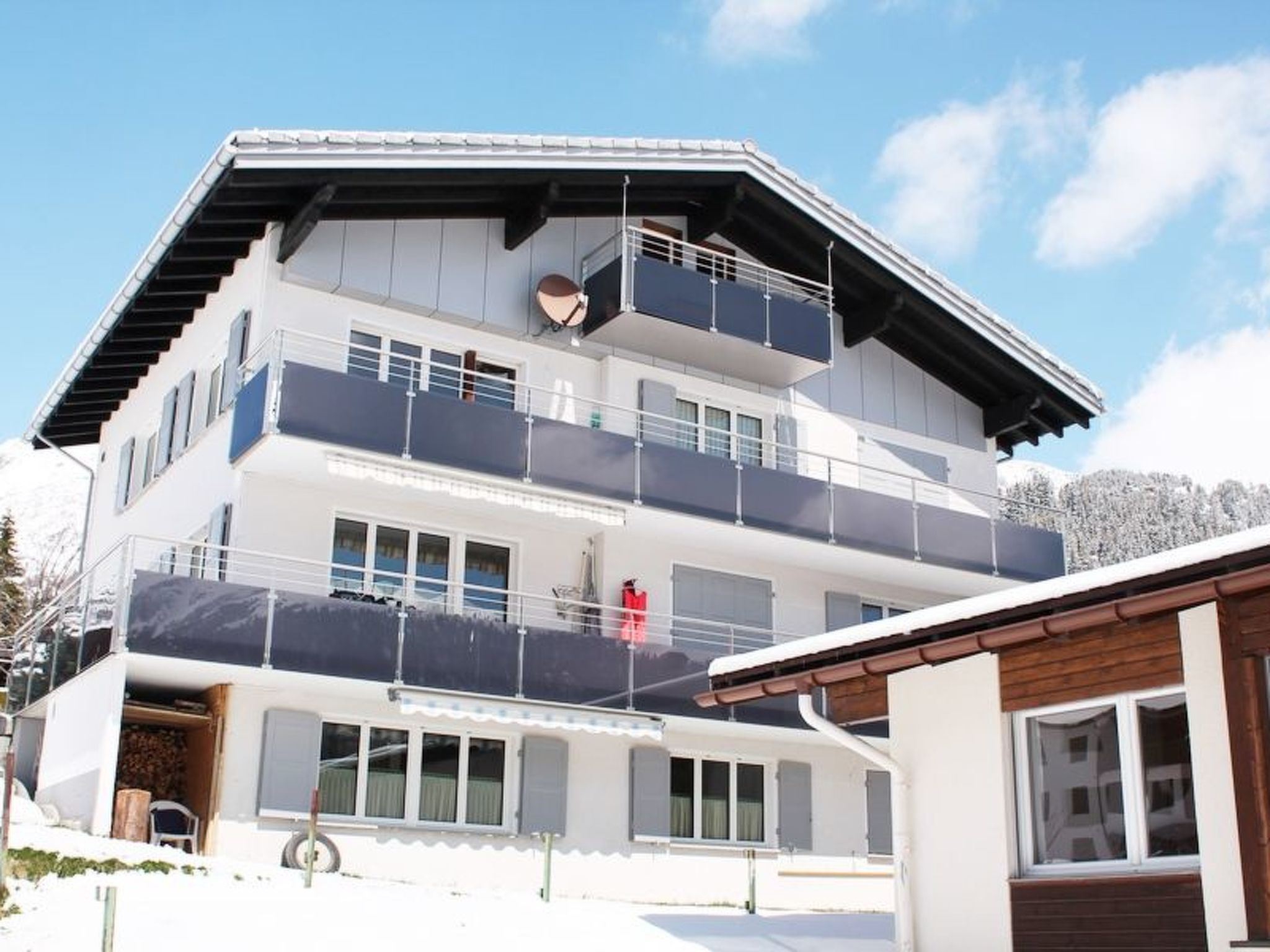 Un edificio de varios pisos con balcones, ventanas amplias y una pista de esquí al fondo.