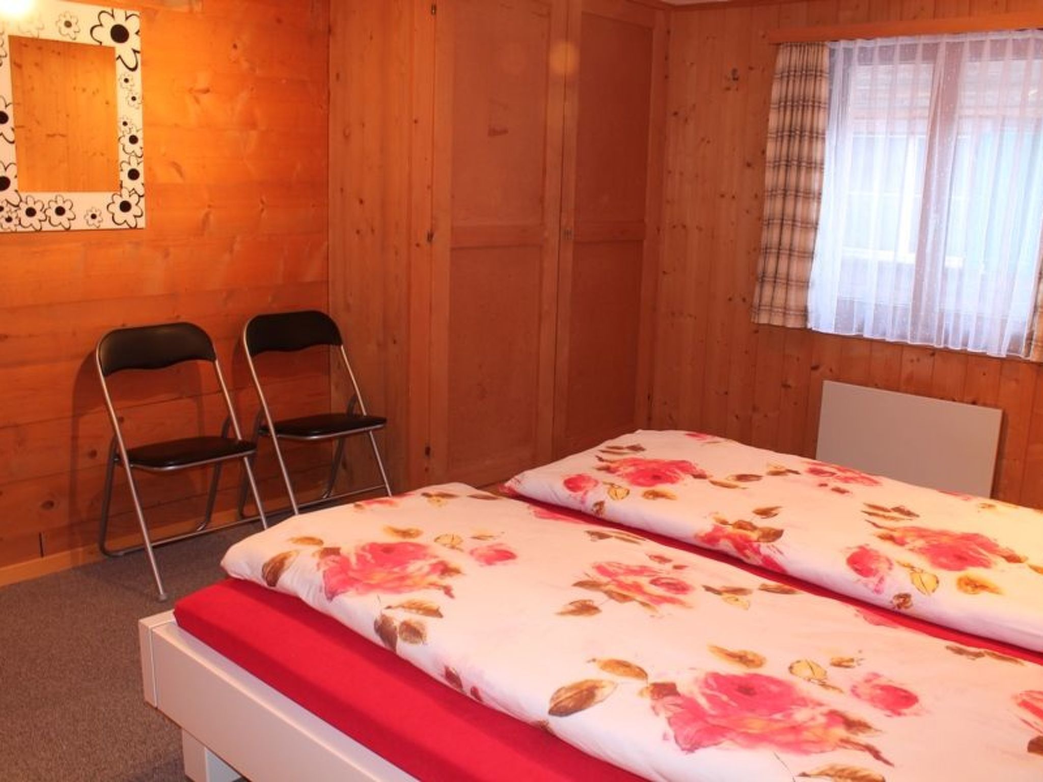 Une chambre avec deux lits, un miroir et deux chaises.